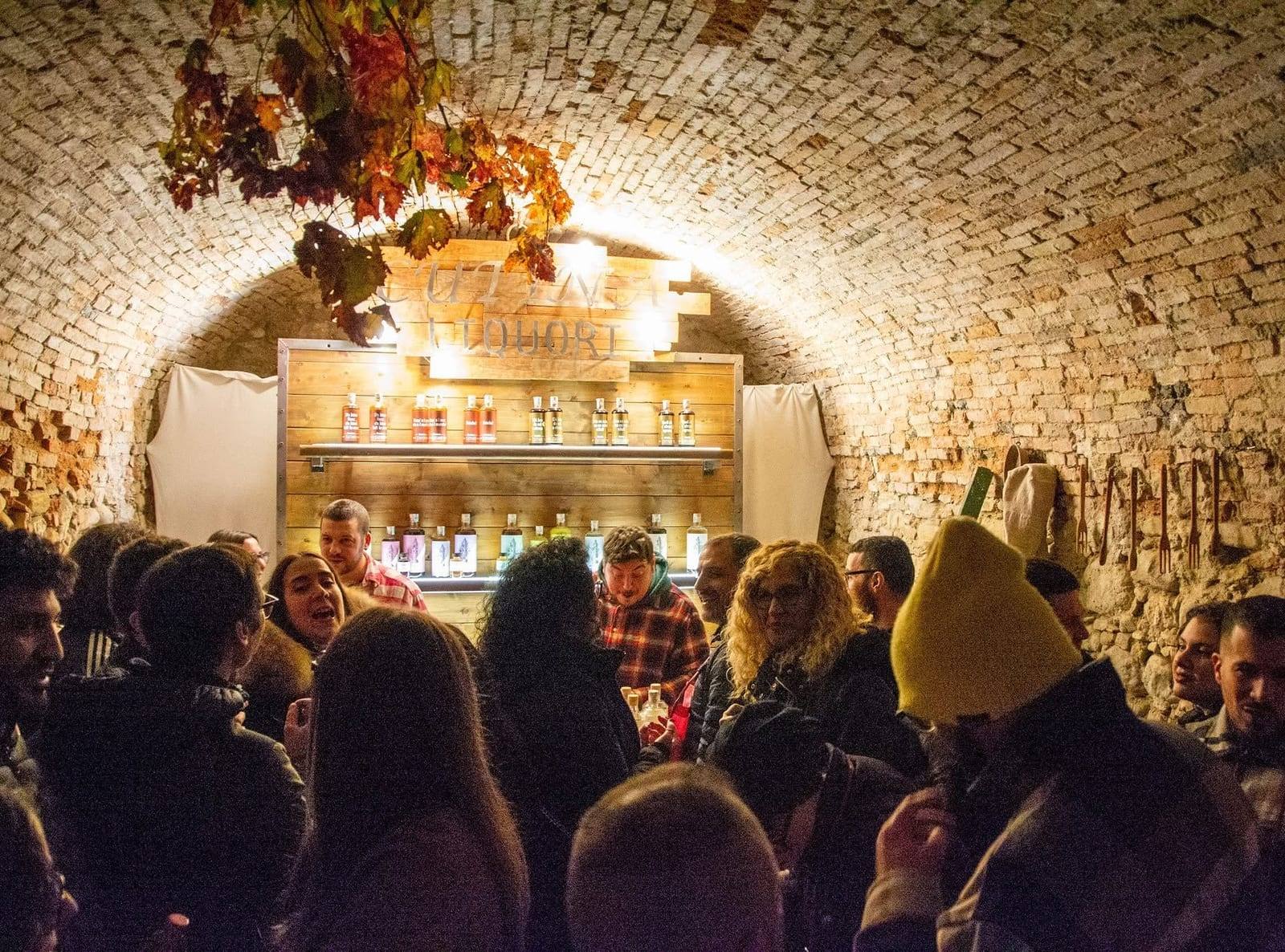Cantina con volta a botte in mattoni e visitatori al bancone