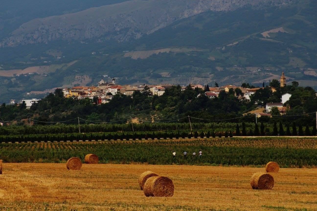 Catignano sulla collina, con i campi di balle di fieno e le montagne sullo sfondo