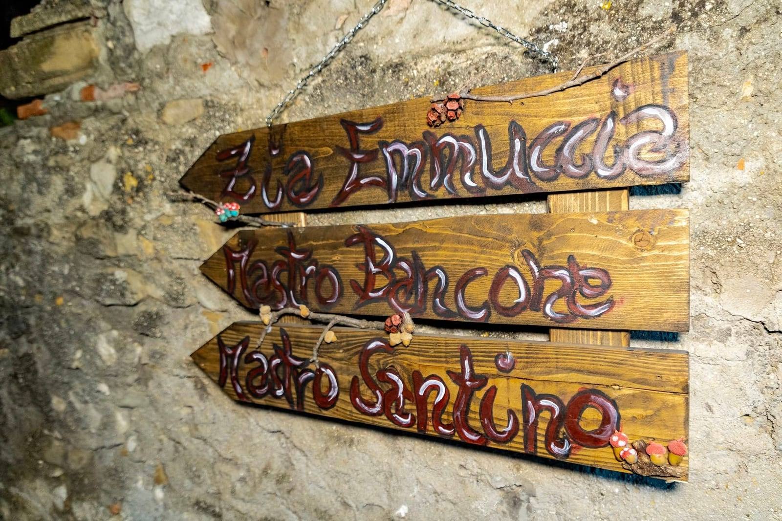 Insegne in legno con i nomi delle cantine su un muro in pietra