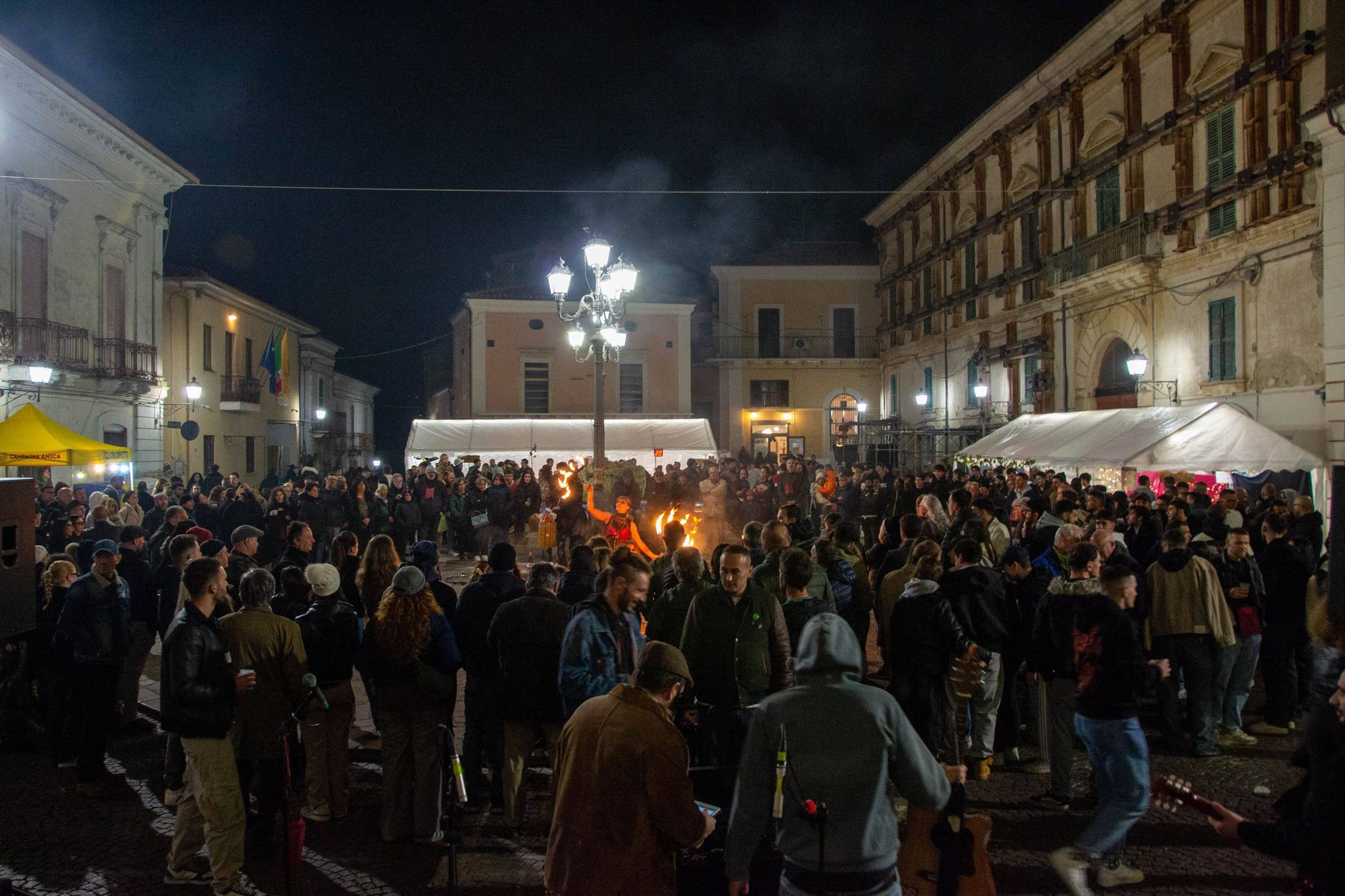 La piazza di Catignano gremita di notte, tra palazzi illuminati e gazebo bianchi