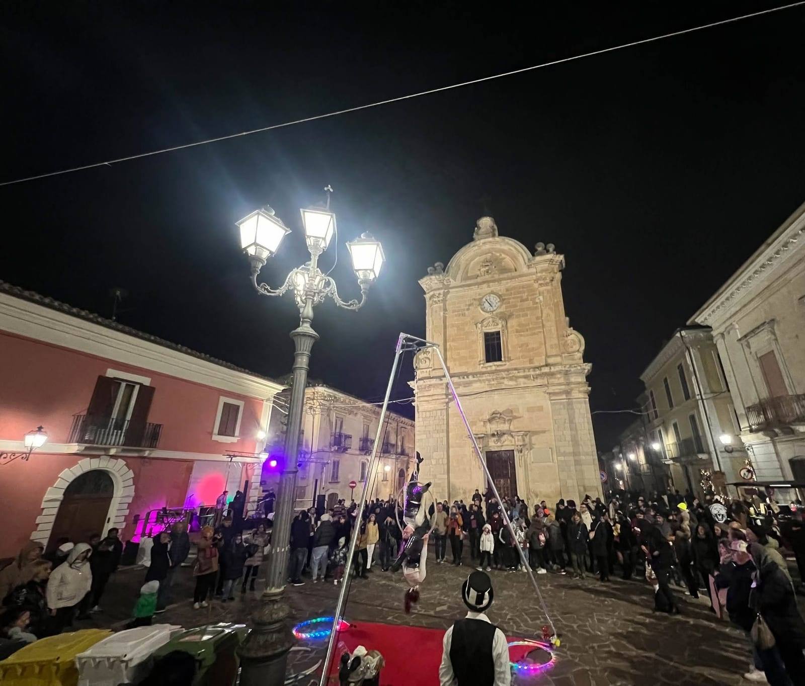 Un’acrobata aerea nel cerchio davanti alla facciata della chiesa illuminata