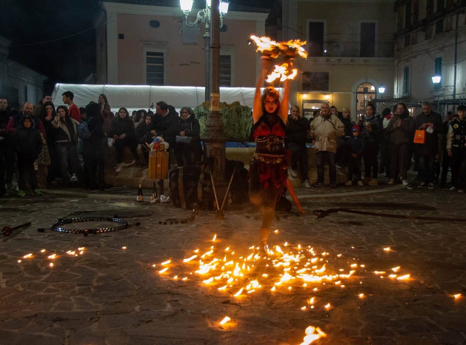 Artista con i ventagli di fuoco alzati su un tappeto di fiammelle